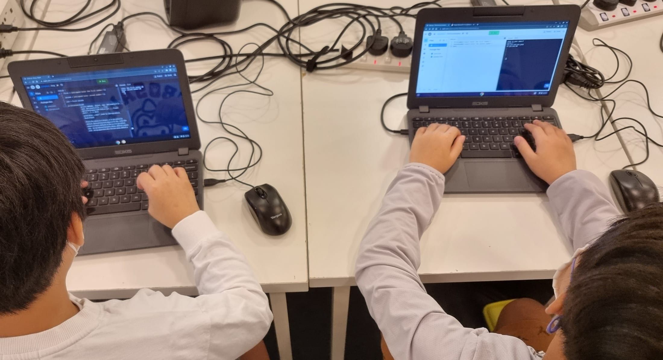 Two students pair-programming a Scratch project on their laptops