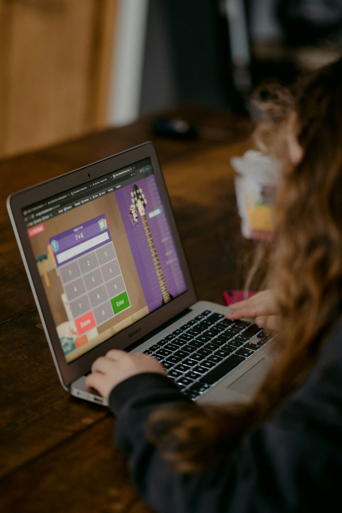 A child working through a times-table game on a laptop at home
