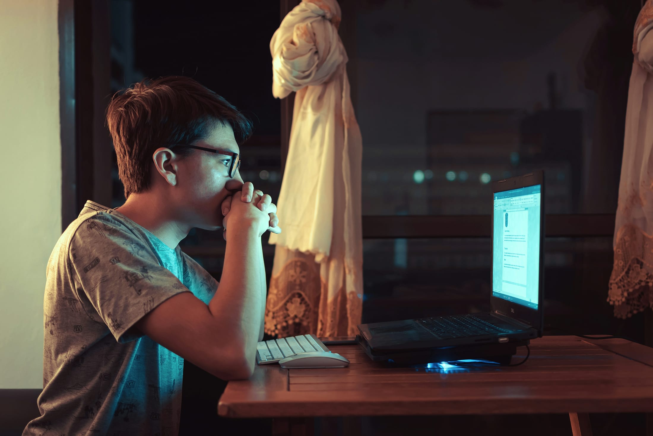 A teenager thinking through a problem at their laptop