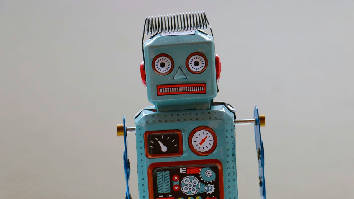 A retro blue tin toy robot with dials and gears on its chest, standing against a plain grey background