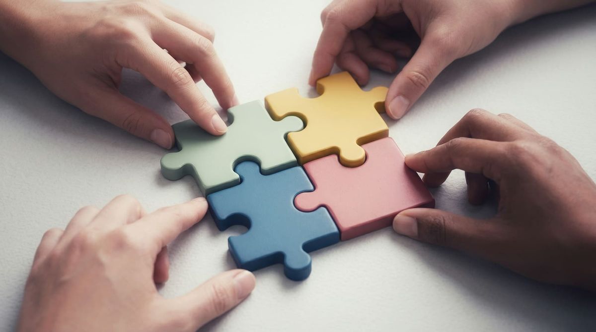 Four hands fitting coloured puzzle pieces together, representing a student putting understanding together instead of copying AI answers